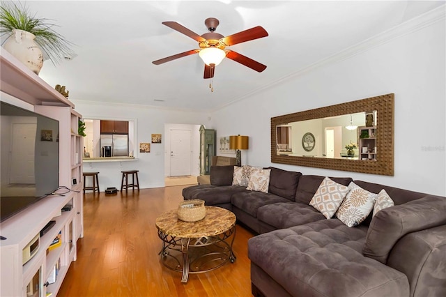 living area featuring a ceiling fan, crown molding, and wood finished floors