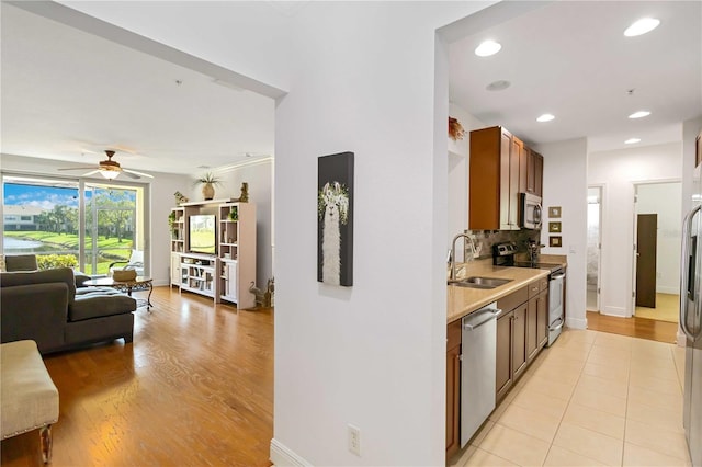 kitchen with a sink, open floor plan, light countertops, appliances with stainless steel finishes, and tasteful backsplash