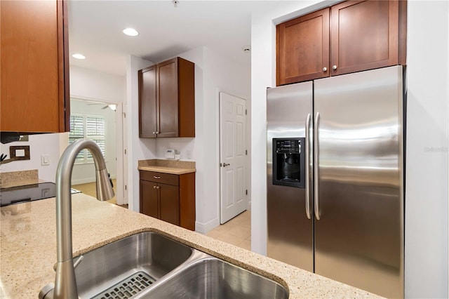 kitchen with stainless steel fridge, recessed lighting, light stone counters, a sink, and light tile patterned flooring