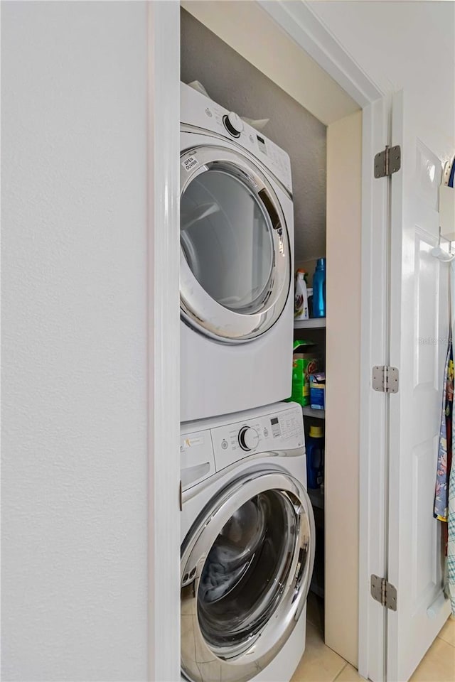 laundry area with stacked washer / dryer, laundry area, and light tile patterned floors