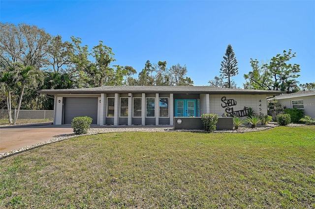 mid-century inspired home featuring a garage, a front yard, concrete driveway, and fence