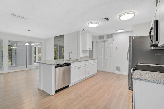 kitchen featuring appliances with stainless steel finishes, pendant lighting, white cabinetry, and visible vents