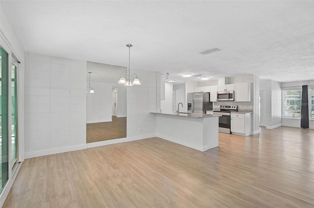 kitchen with visible vents, light wood-style flooring, appliances with stainless steel finishes, white cabinetry, and pendant lighting