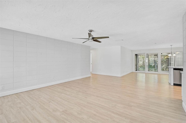 unfurnished living room with a textured ceiling, light wood finished floors, ceiling fan with notable chandelier, and baseboards