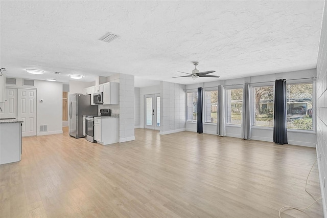 unfurnished living room with light wood-style floors, visible vents, ceiling fan, and a textured ceiling