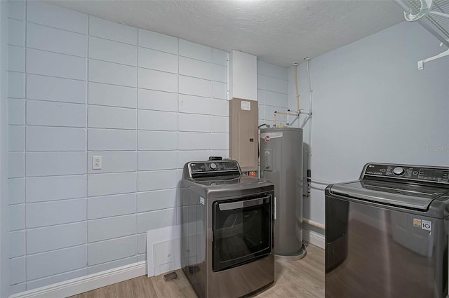 washroom featuring a textured ceiling, laundry area, light wood-style floors, water heater, and independent washer and dryer