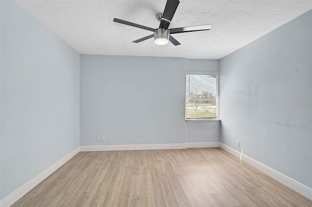 spare room featuring a ceiling fan, light wood-type flooring, a textured ceiling, and baseboards