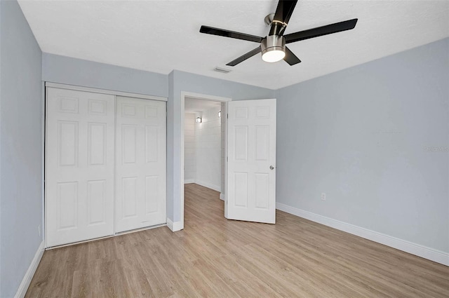 unfurnished bedroom with a closet, baseboards, and light wood finished floors