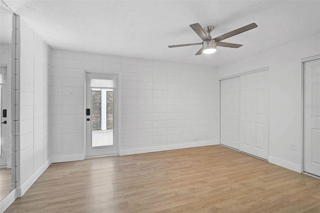 spare room with a ceiling fan, light wood-type flooring, and baseboards