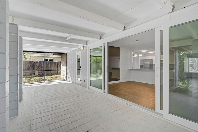 unfurnished sunroom featuring a wealth of natural light, beam ceiling, and a notable chandelier