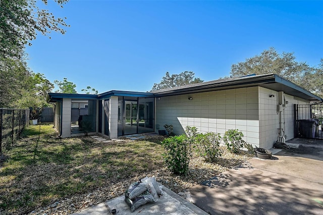 mid-century home featuring concrete block siding, fence, and a patio