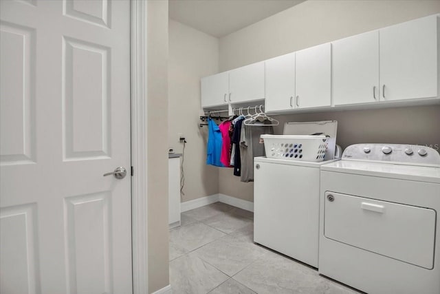 washroom featuring washer and dryer, cabinet space, and baseboards