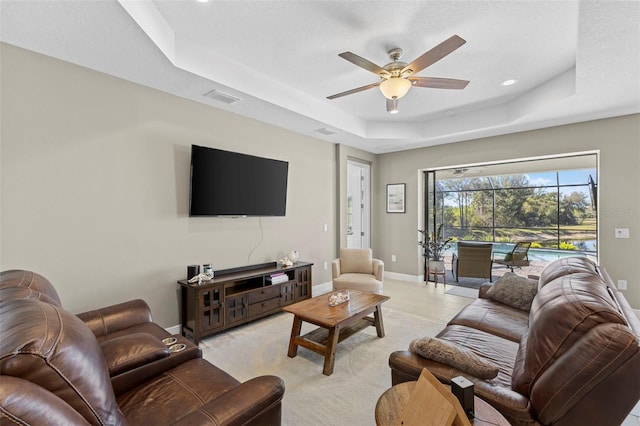 living room featuring a tray ceiling, recessed lighting, visible vents, a ceiling fan, and baseboards