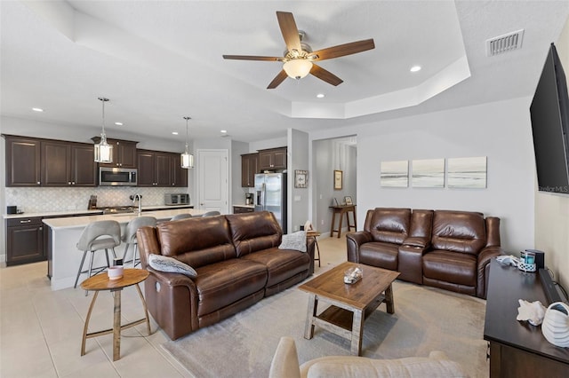 living room with light tile patterned floors, visible vents, ceiling fan, a tray ceiling, and recessed lighting