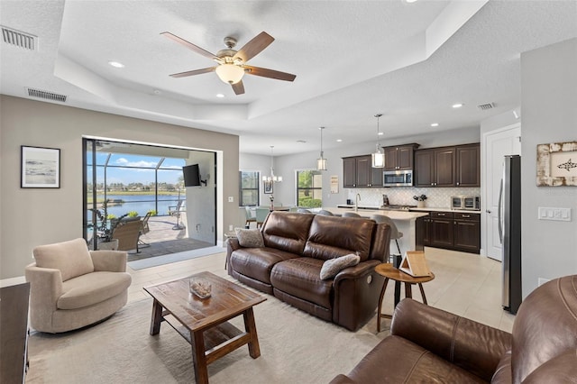 living area with visible vents, a raised ceiling, a textured ceiling, and recessed lighting