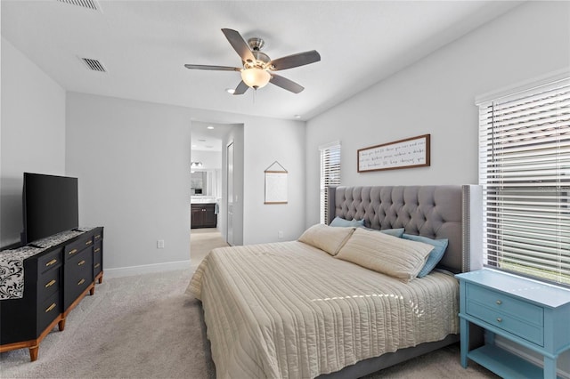 bedroom with ceiling fan, connected bathroom, light carpet, visible vents, and baseboards