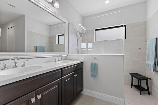 full bath with double vanity, walk in shower, a sink, and tile patterned floors