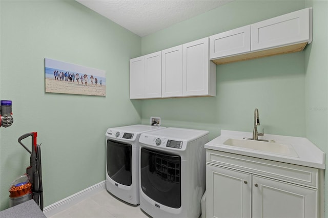 washroom featuring light tile patterned flooring, washing machine and dryer, a sink, baseboards, and cabinet space