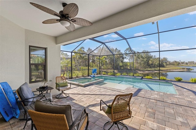 view of pool with glass enclosure, a water view, a ceiling fan, a pool with connected hot tub, and a patio area