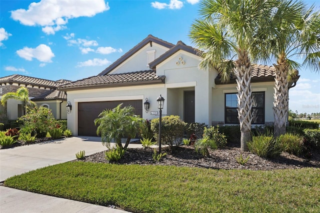 mediterranean / spanish-style home with a tile roof, stucco siding, a garage, driveway, and a front lawn