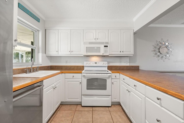 kitchen with light tile patterned floors, ornamental molding, white cabinetry, a sink, and white appliances