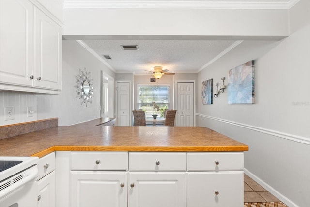 kitchen featuring a textured ceiling, a peninsula, visible vents, white cabinetry, and crown molding