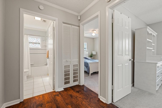 hallway with a textured ceiling, dark wood finished floors, and crown molding