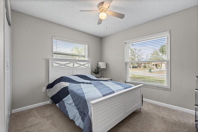 bedroom with light carpet, ceiling fan, multiple windows, and a textured ceiling