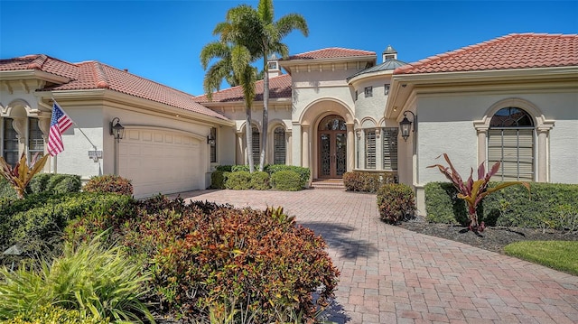 view of front of home featuring a garage, french doors, a tile roof, and stucco siding