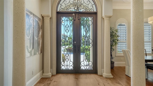 entrance foyer with french doors, plenty of natural light, wood finished floors, and decorative columns