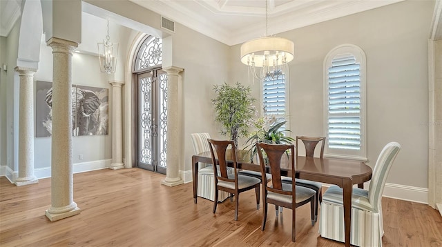 dining area featuring crown molding, decorative columns, a notable chandelier, visible vents, and light wood-type flooring