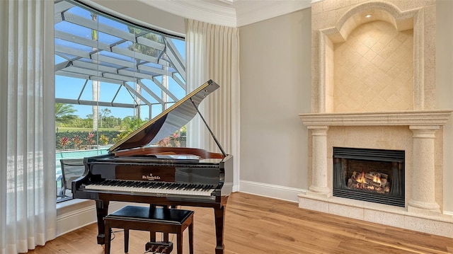 sitting room featuring crown molding, baseboards, wood finished floors, and a lit fireplace