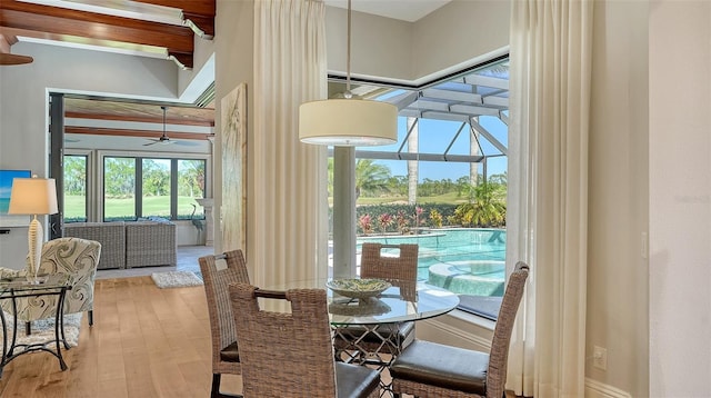 dining room with a sunroom, ceiling fan, a towering ceiling, and wood finished floors