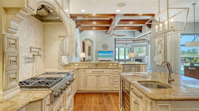 kitchen featuring stainless steel appliances, a sink, light wood finished floors, and light stone countertops