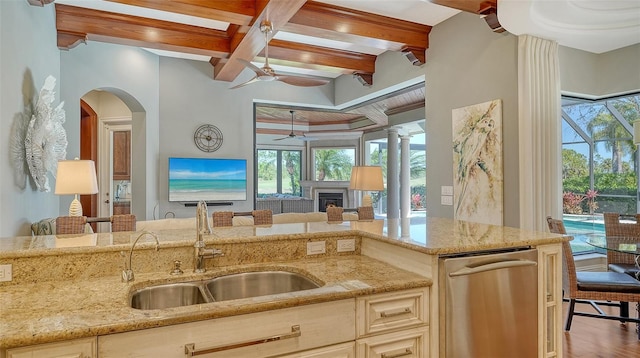 kitchen with coffered ceiling, light stone counters, beamed ceiling, a fireplace, and a sink