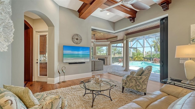 living room featuring beam ceiling, a ceiling fan, a sunroom, wood finished floors, and baseboards