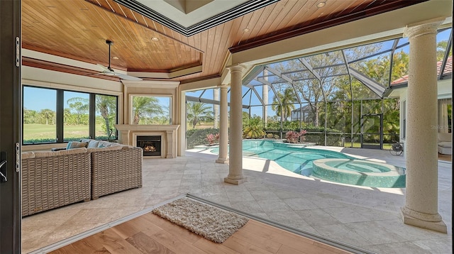 exterior space with ceiling fan, glass enclosure, a patio, a pool with connected hot tub, and a lit fireplace