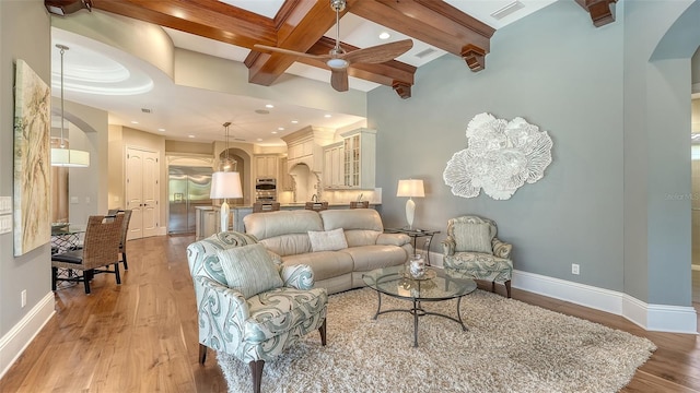 living area featuring arched walkways, baseboards, visible vents, and light wood-style floors