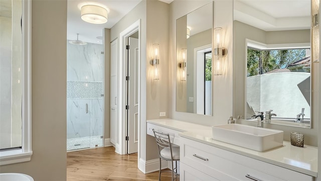 full bath with a marble finish shower, baseboards, wood finished floors, and vanity