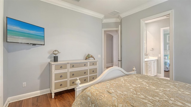 bedroom featuring baseboards, visible vents, ensuite bath, ornamental molding, and wood finished floors