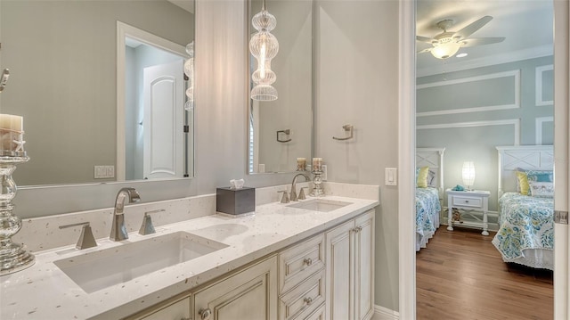 full bath featuring connected bathroom, double vanity, a sink, and wood finished floors