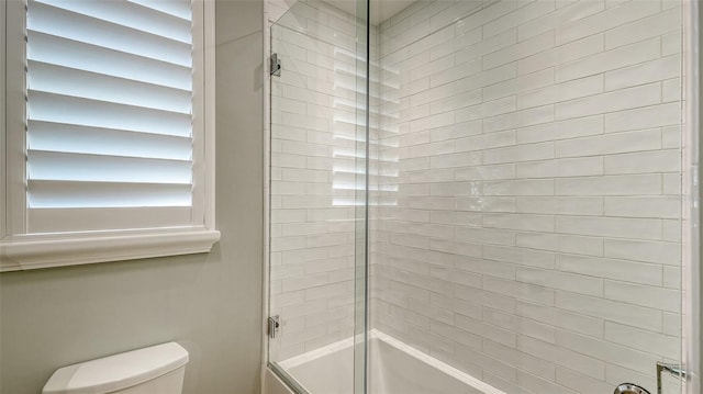 bathroom featuring enclosed tub / shower combo and toilet