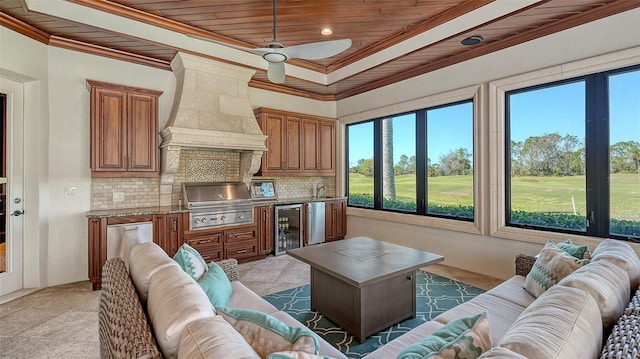 living area featuring wine cooler, wooden ceiling, a ceiling fan, a raised ceiling, and crown molding