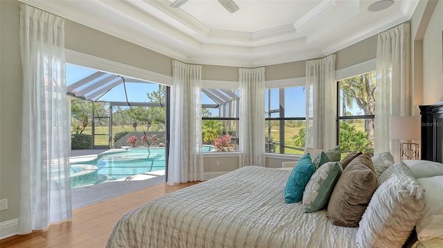 bedroom with a raised ceiling, a sunroom, ornamental molding, wood finished floors, and access to exterior