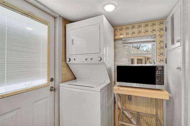 washroom featuring stacked washer and clothes dryer and laundry area