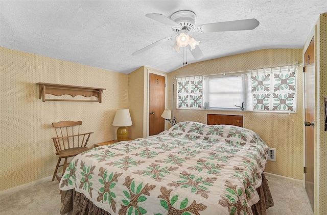 bedroom featuring light carpet, wallpapered walls, visible vents, lofted ceiling, and a textured ceiling