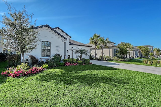 mediterranean / spanish home with a garage, driveway, a front lawn, and stucco siding