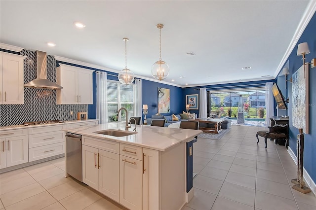 kitchen featuring an island with sink, wall chimney exhaust hood, open floor plan, light countertops, and a sink