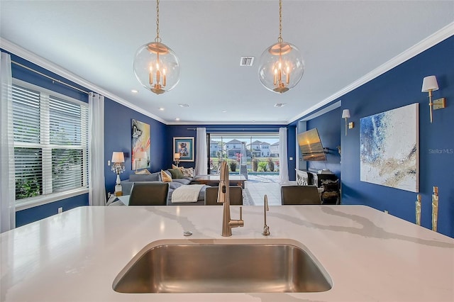 kitchen featuring open floor plan, a sink, visible vents, and crown molding