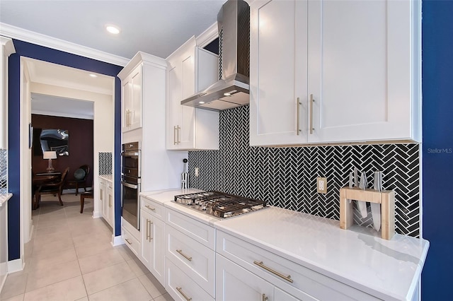 kitchen featuring wall chimney exhaust hood, light countertops, stainless steel appliances, white cabinetry, and light tile patterned flooring